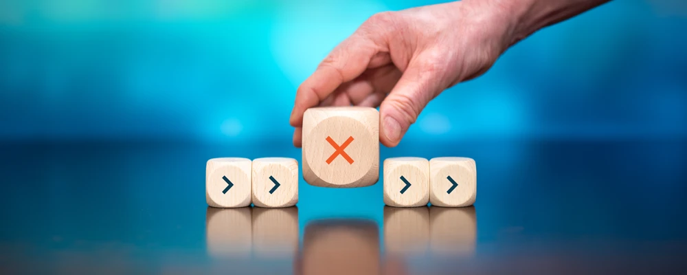 Hand placing large die with an X in-between 4 smaller die, 2 on the right, 2 on the left, all with arrows pointing right.