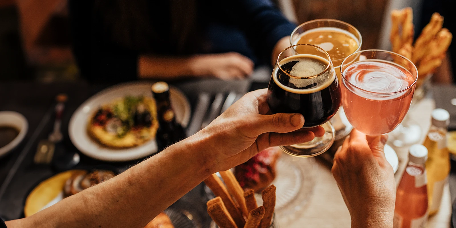 Friends cheers with beverages at dinner