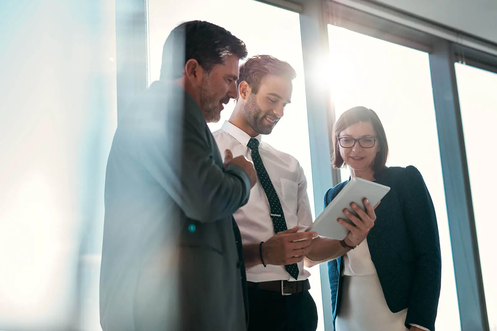 Three business people standing and reading a document together