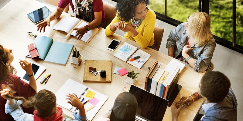 A group of diverse workers attend a meeting together and discuss.