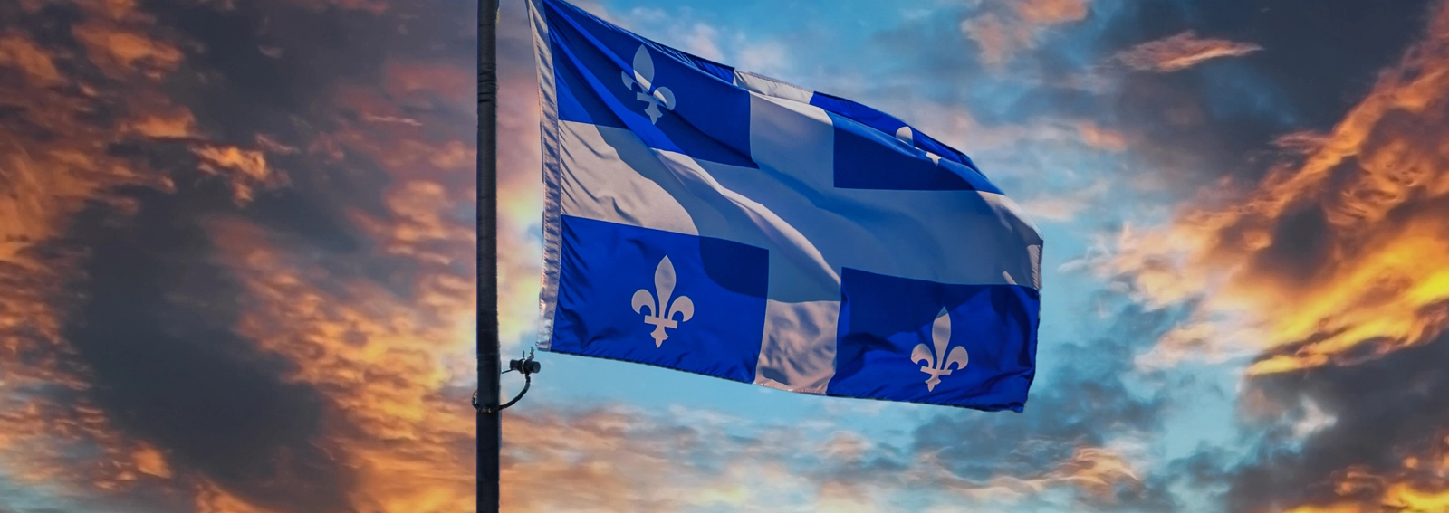 Drapeau du Québec avec un ciel coucher de soleil en arrière-plan.