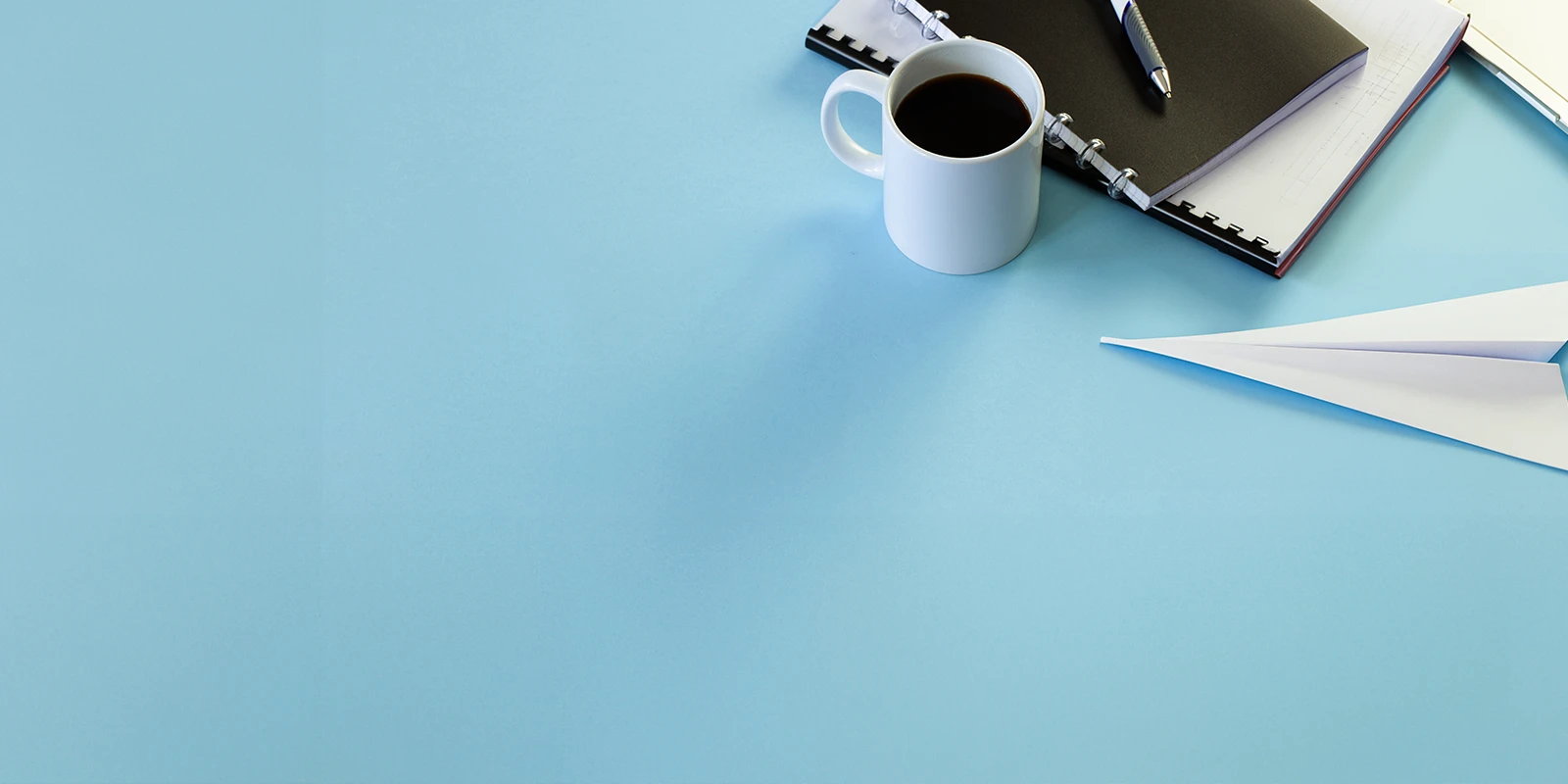 Coffee cup and a notebook on blue background