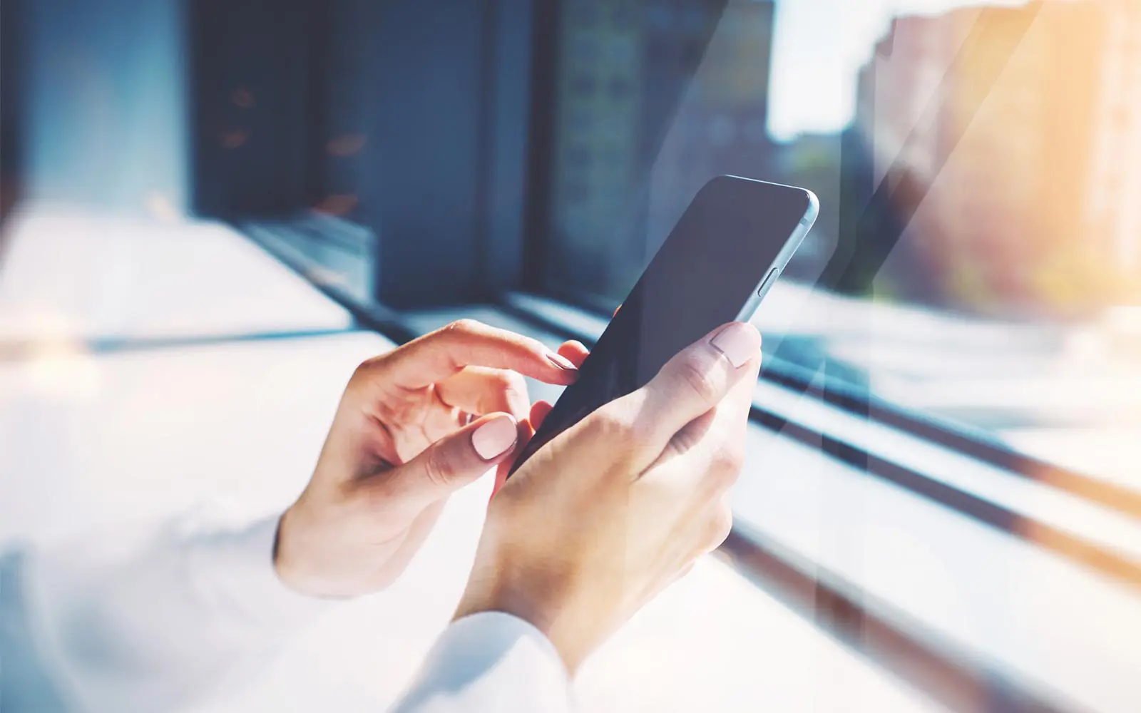 Close-up of someone looking at a smart phone in front of a window