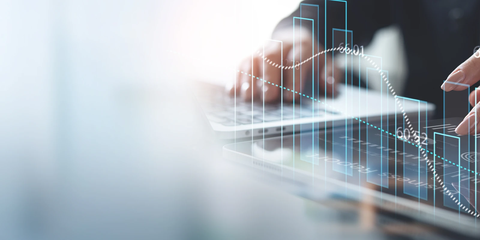 Close up of a person typing on a laptop with graphs in the foreground.