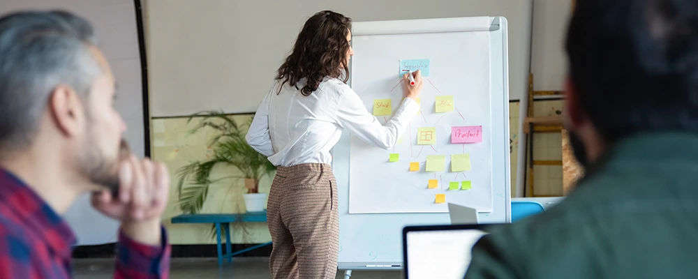 Woman writing on sticky notes on a clip board in front of a group of people