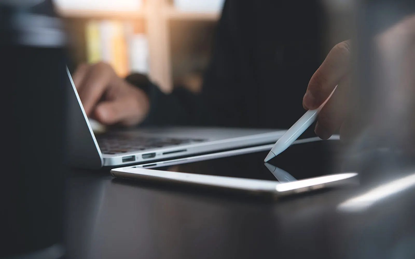 Close-up of someone working on a laptop and tablet