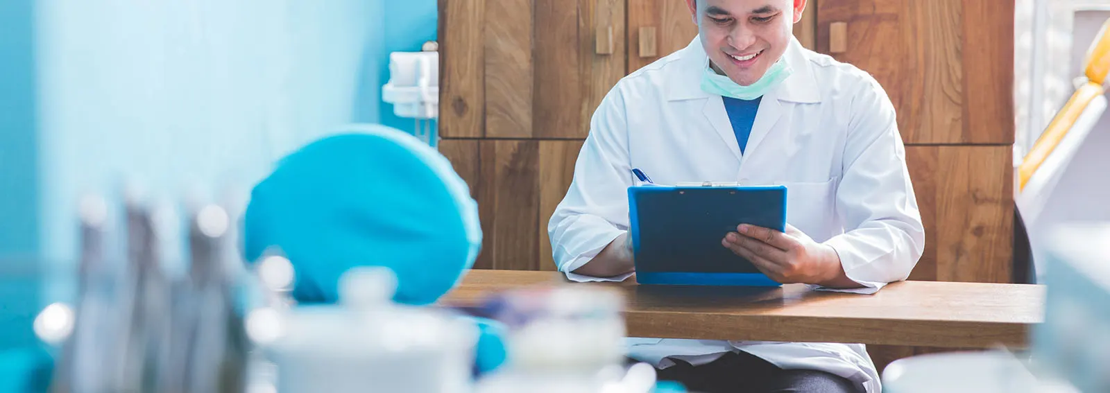 Dentist sitting at a desk in his office working on a tablet.